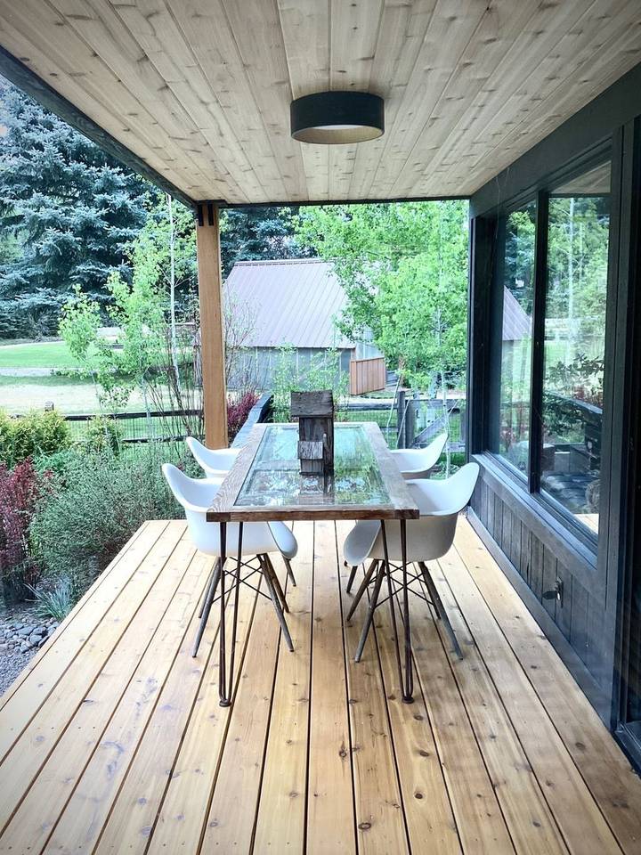 Covered cedar deck with dining table and forest view