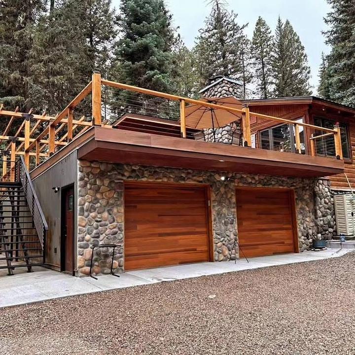 Finished stone-faced garage with cedar doors and cable-rail rooftop deck