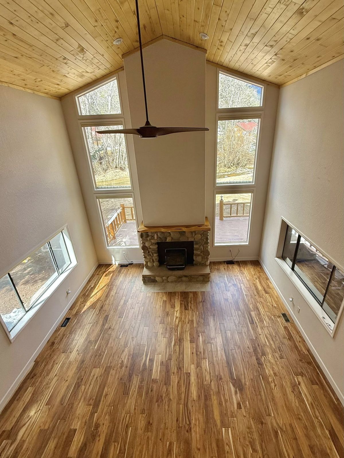 Rebuilt great room with a vaulted pine ceiling and a stone fireplace