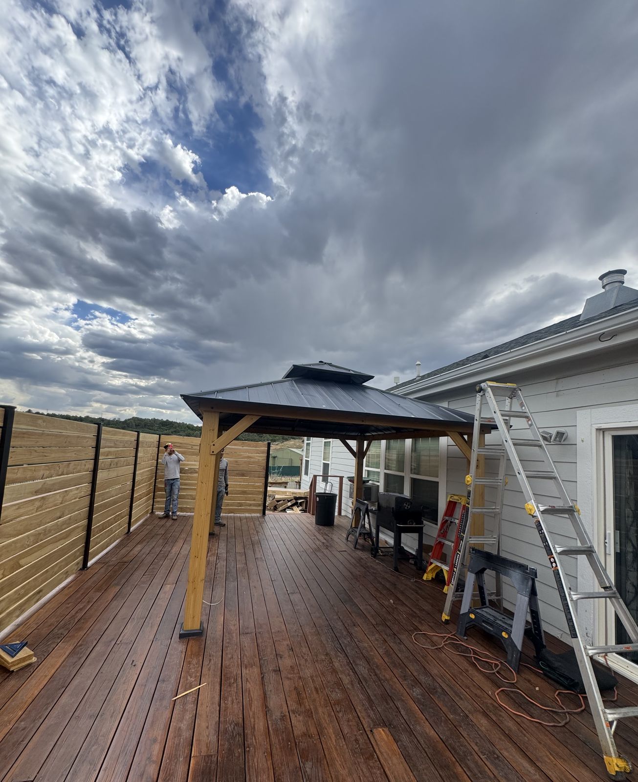 Cedar-post gazebo with a metal roof on a newly stained wood deck