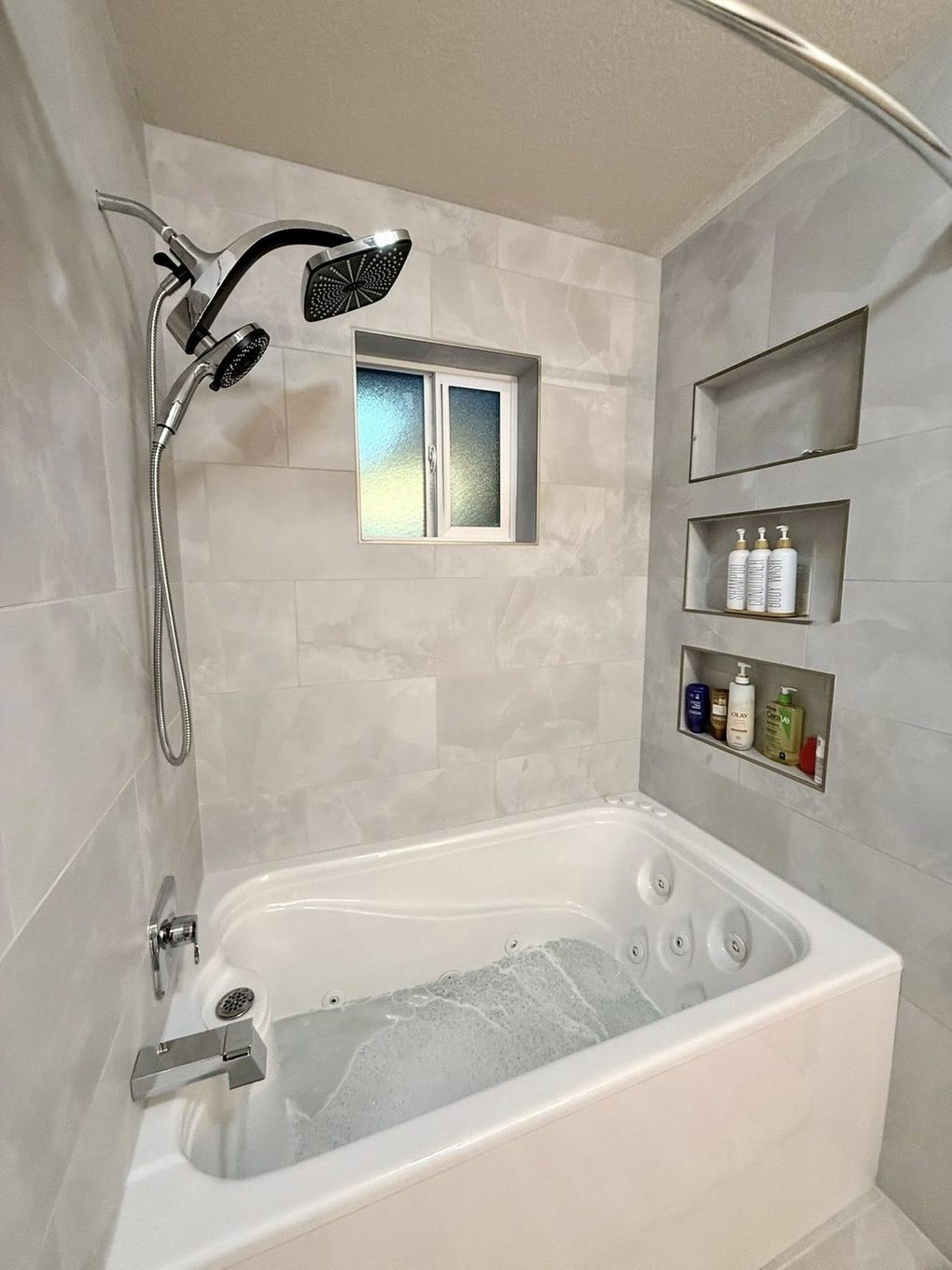 Marble-look tiled tub and shower with built-in niches