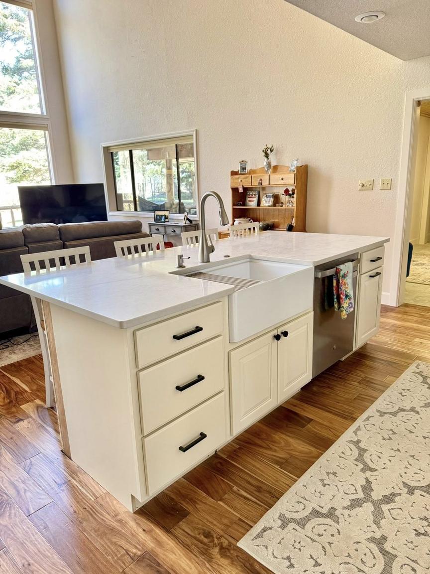 White quartz island with farmhouse sink in an open living space