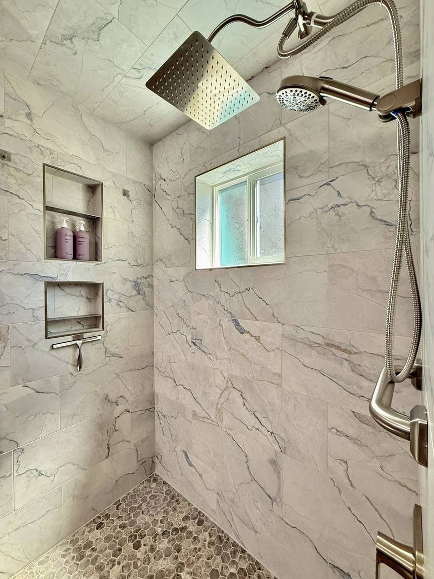 Marble-look walk-in shower with rainfall head and pebble floor