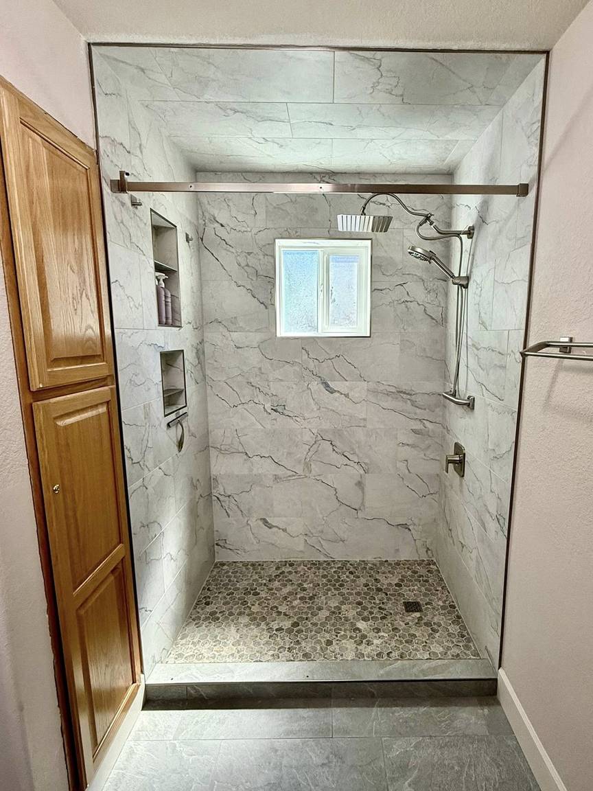 Marble-look walk-in shower with bench and niches