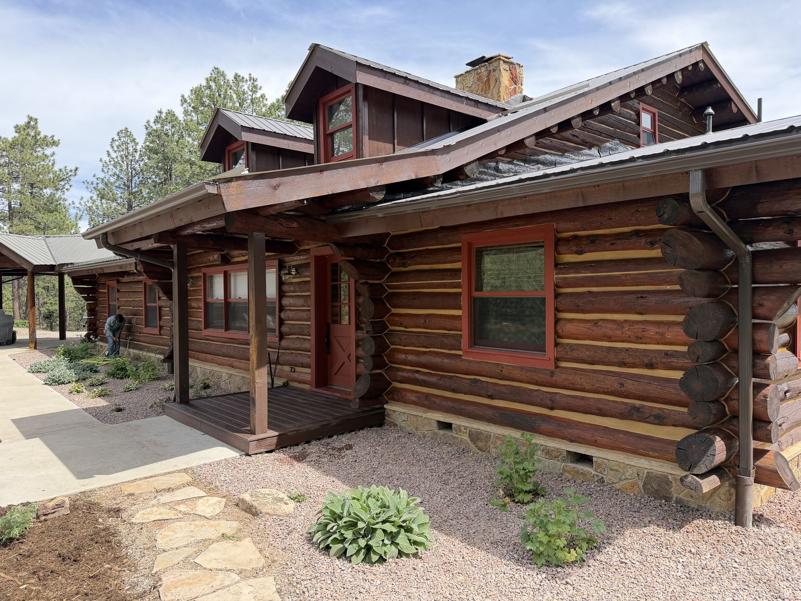 A VR Solutions crew applying fresh exterior stain to a log home, mid-job