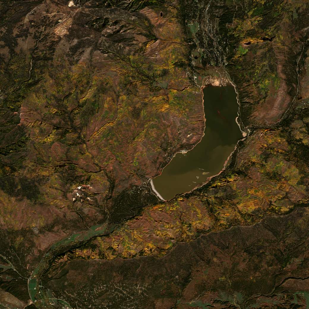 Satellite view of the same reservoir on October 17, 2025, the water risen and turned muddy brown, the north inlet flats now submerged.