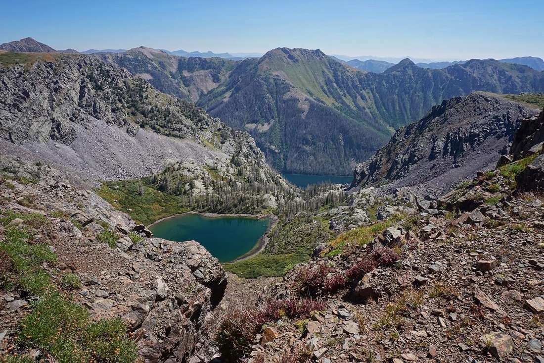 The rim of Cave Basin looking thousands of feet down to two blue-green lakes ringed by rocky peaks