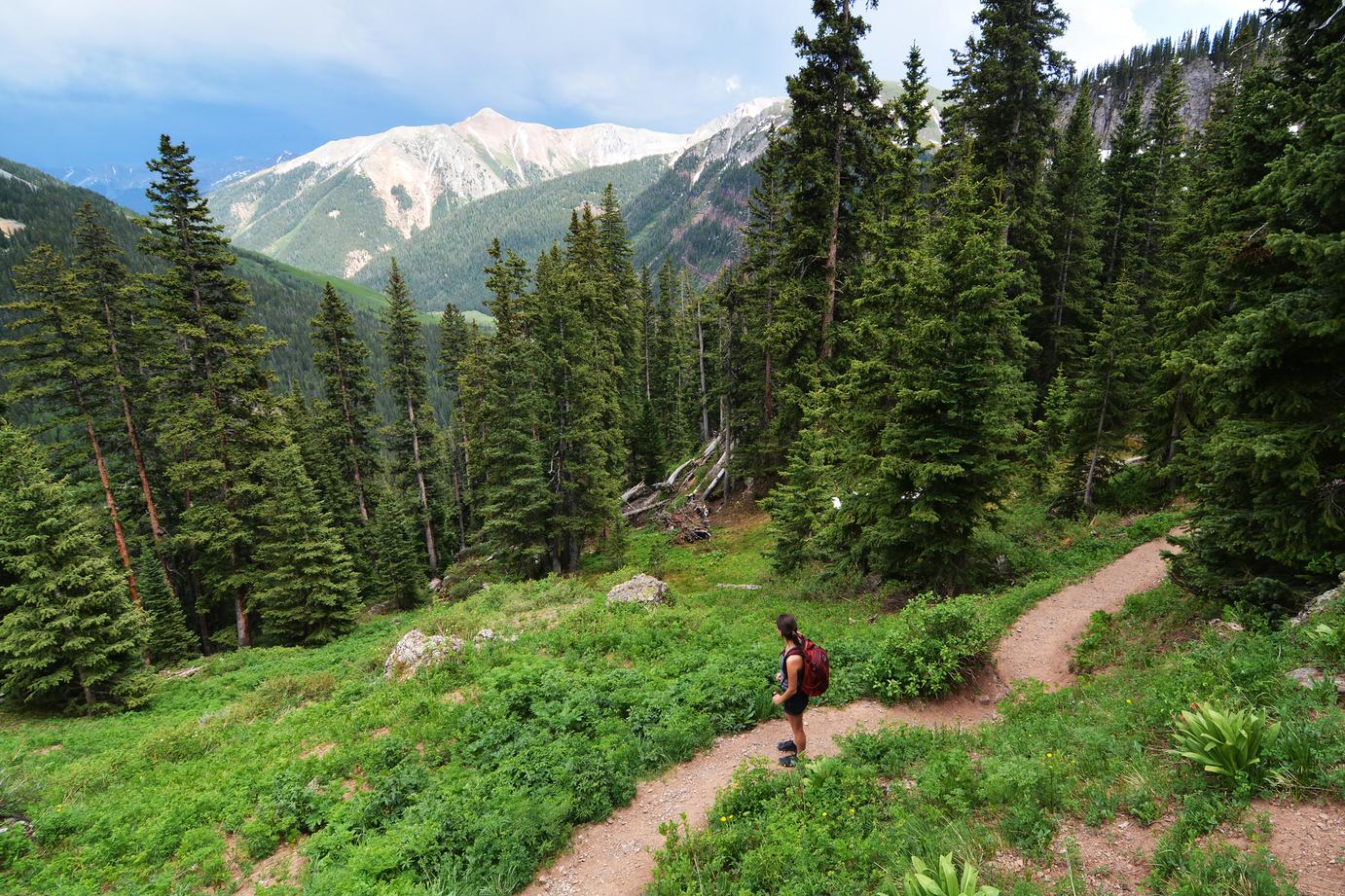 A hiker ascending a trail toward Ice Lake Basin in the San Juan National Forest