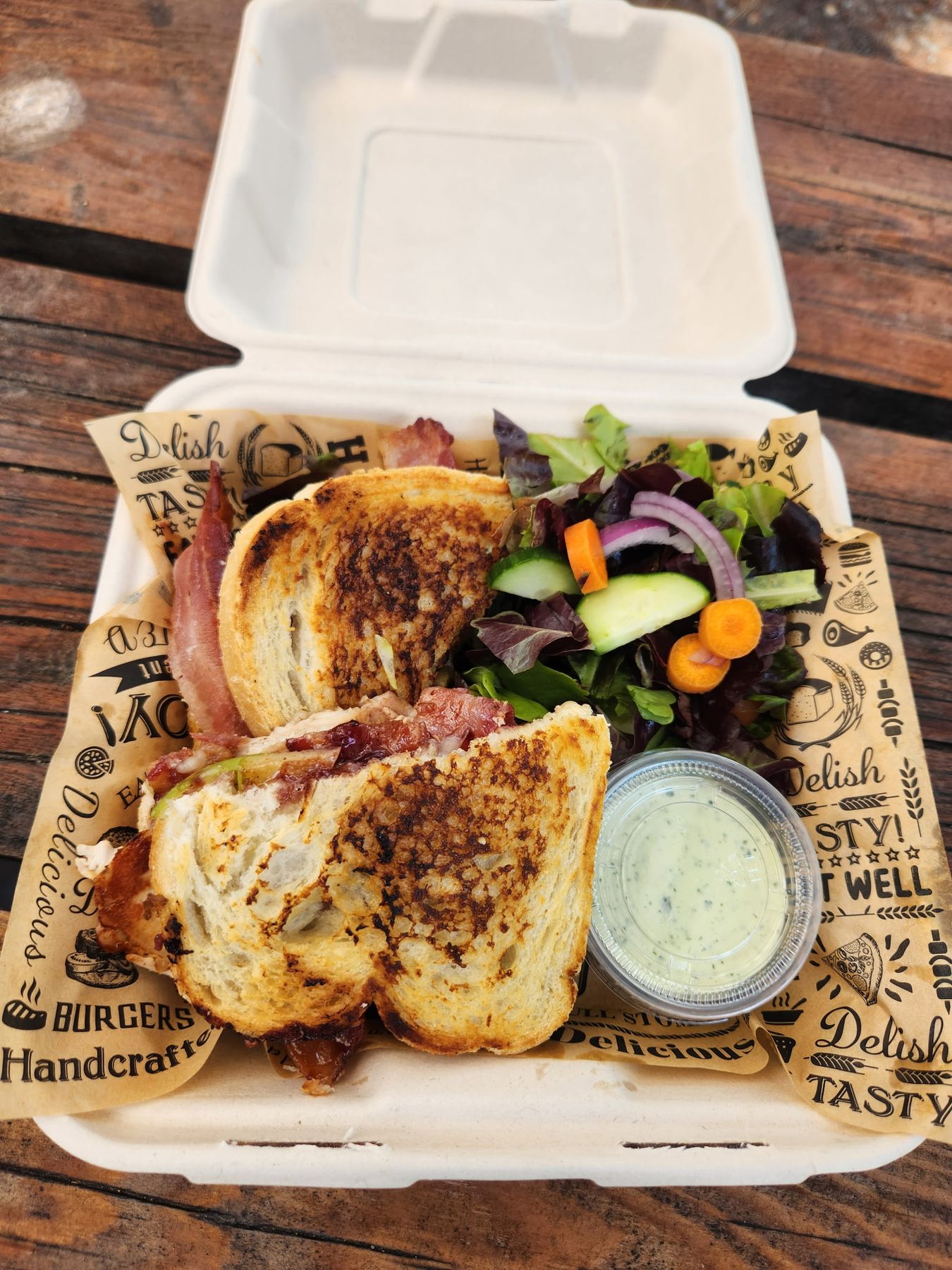 A grilled melt with a house salad and a cup of dipping sauce